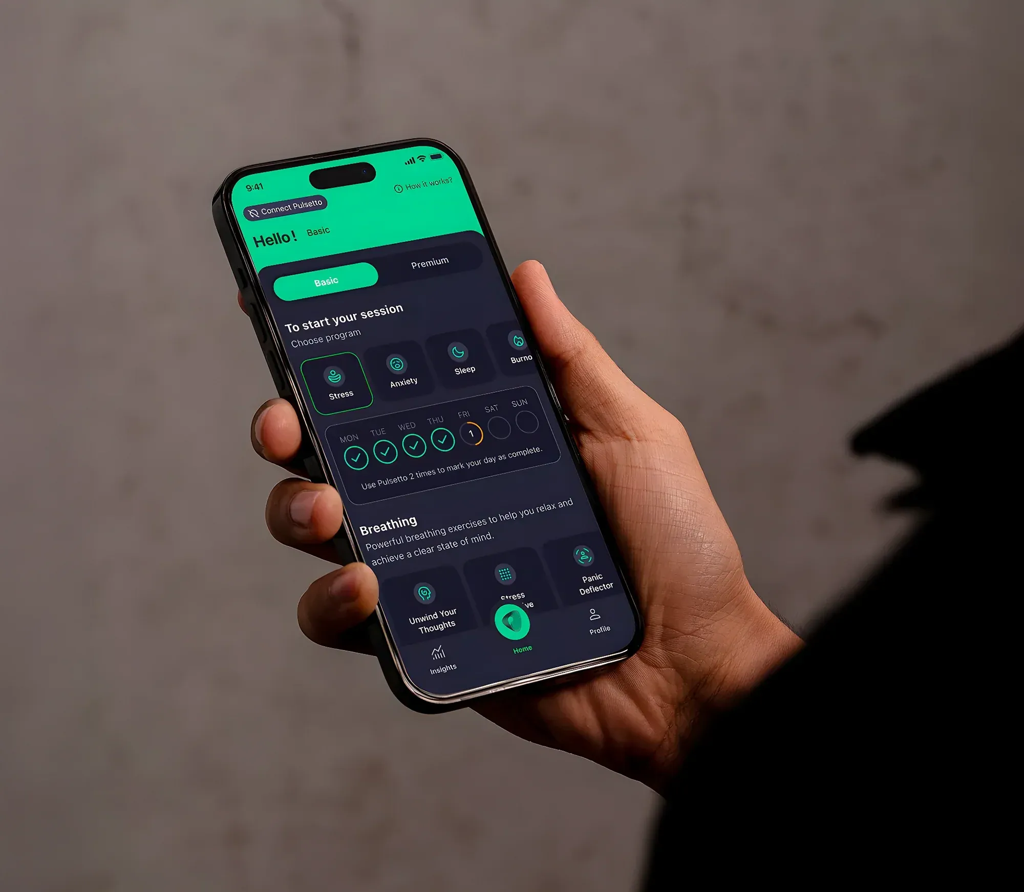 Hand holding a smartphone with the Pulsetto app open, showing Stress, Anxiety, Sleep, and Burnout program selection